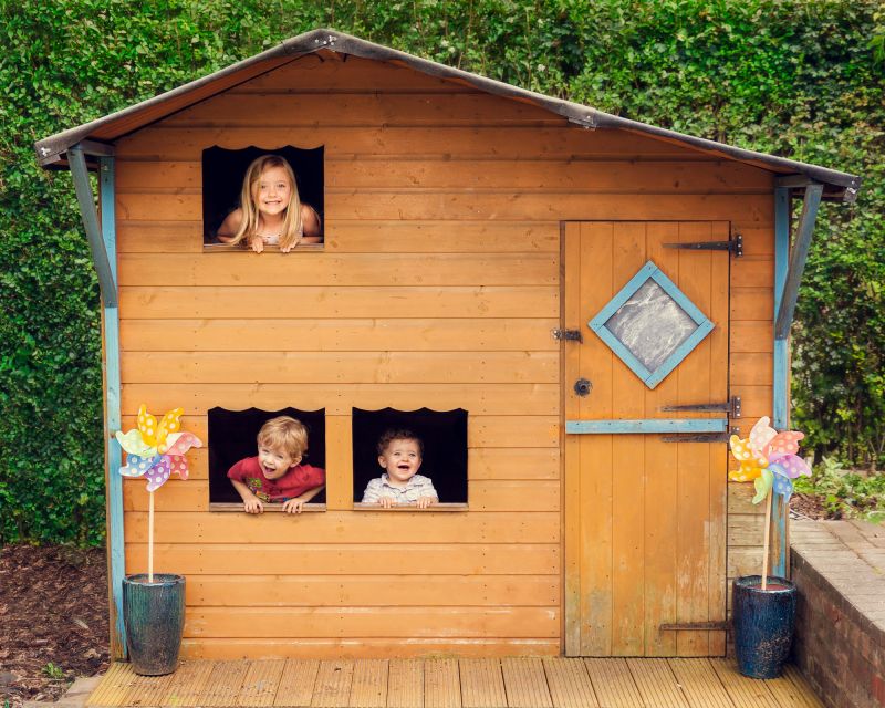 family photography of three children in a wendy house