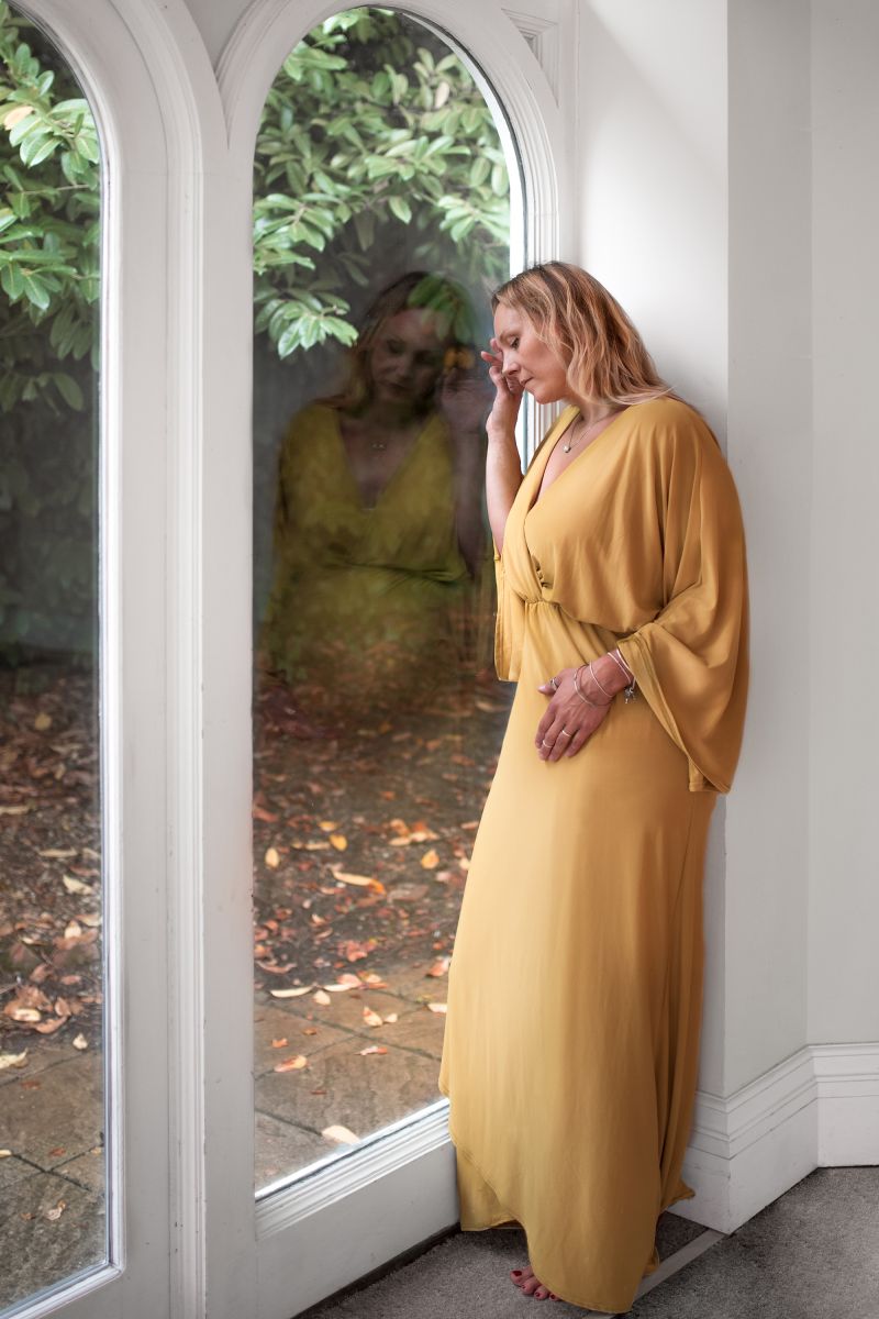 Mother staring out window with reflection