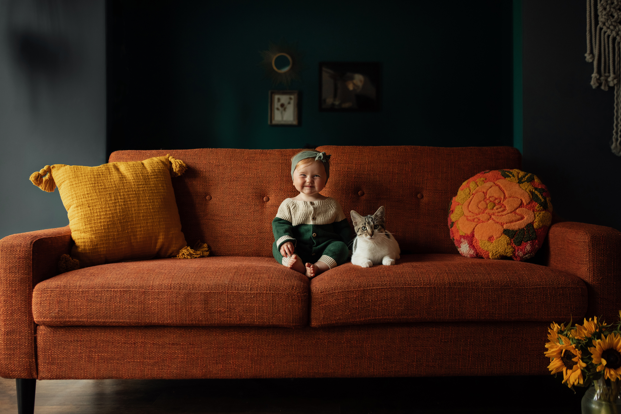 Young girl sits on a couch with a cat.