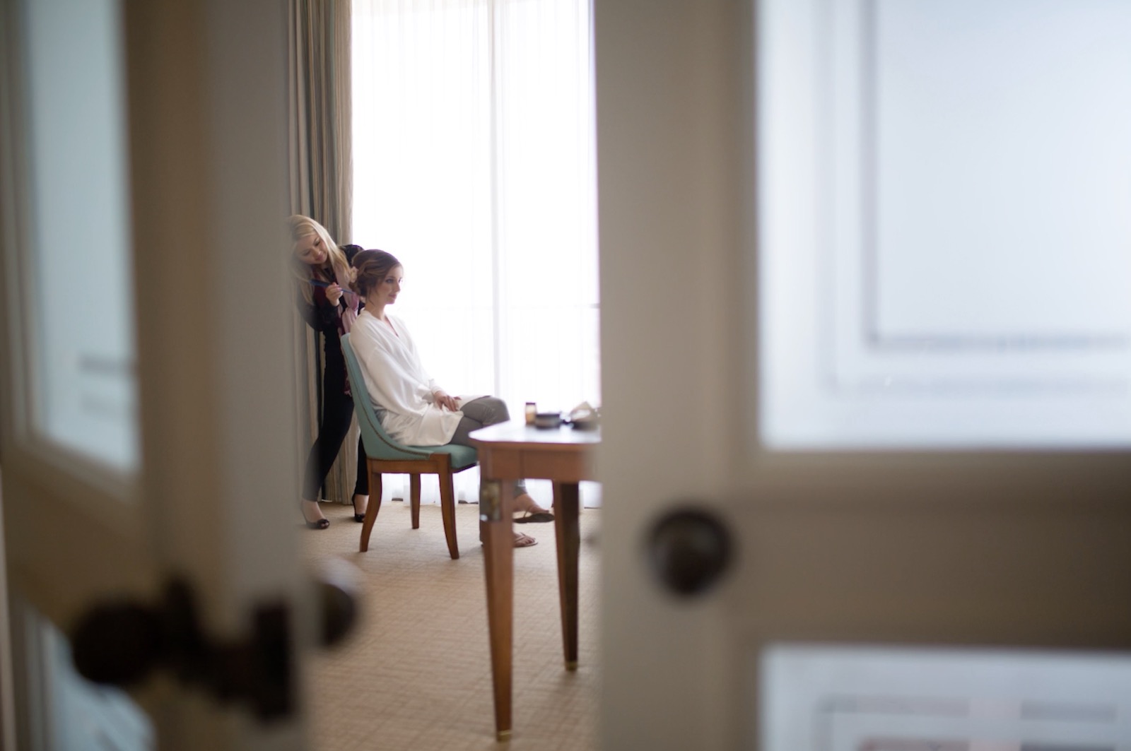 Wide angle environmental shot of bridal prep happening in a sunlit hotel room