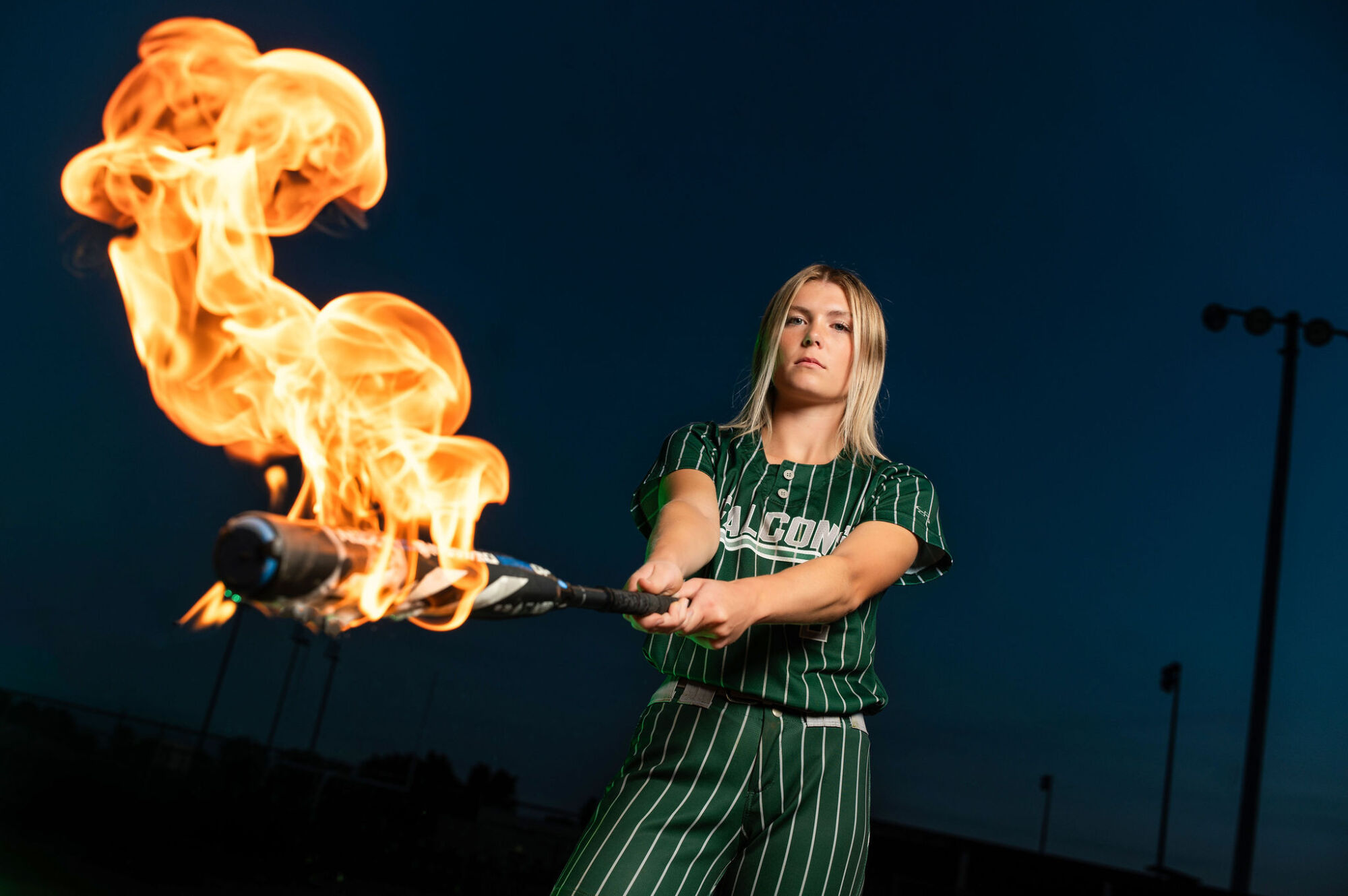 Female softball senior portrait in uniform with glove at the field