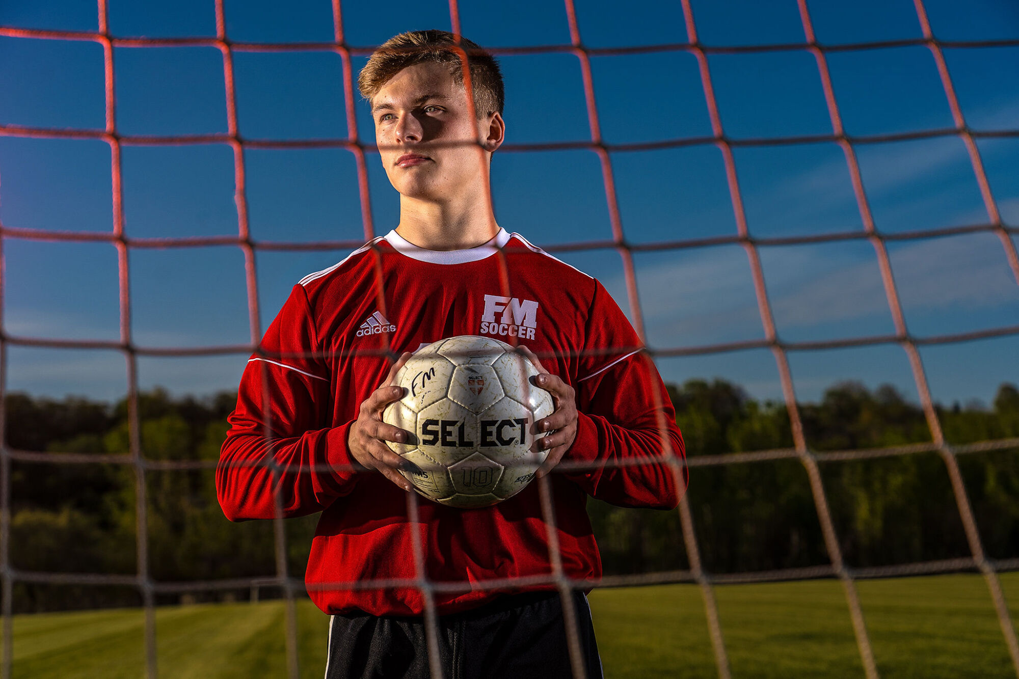 Male soccer player senior portrait in action pose on field