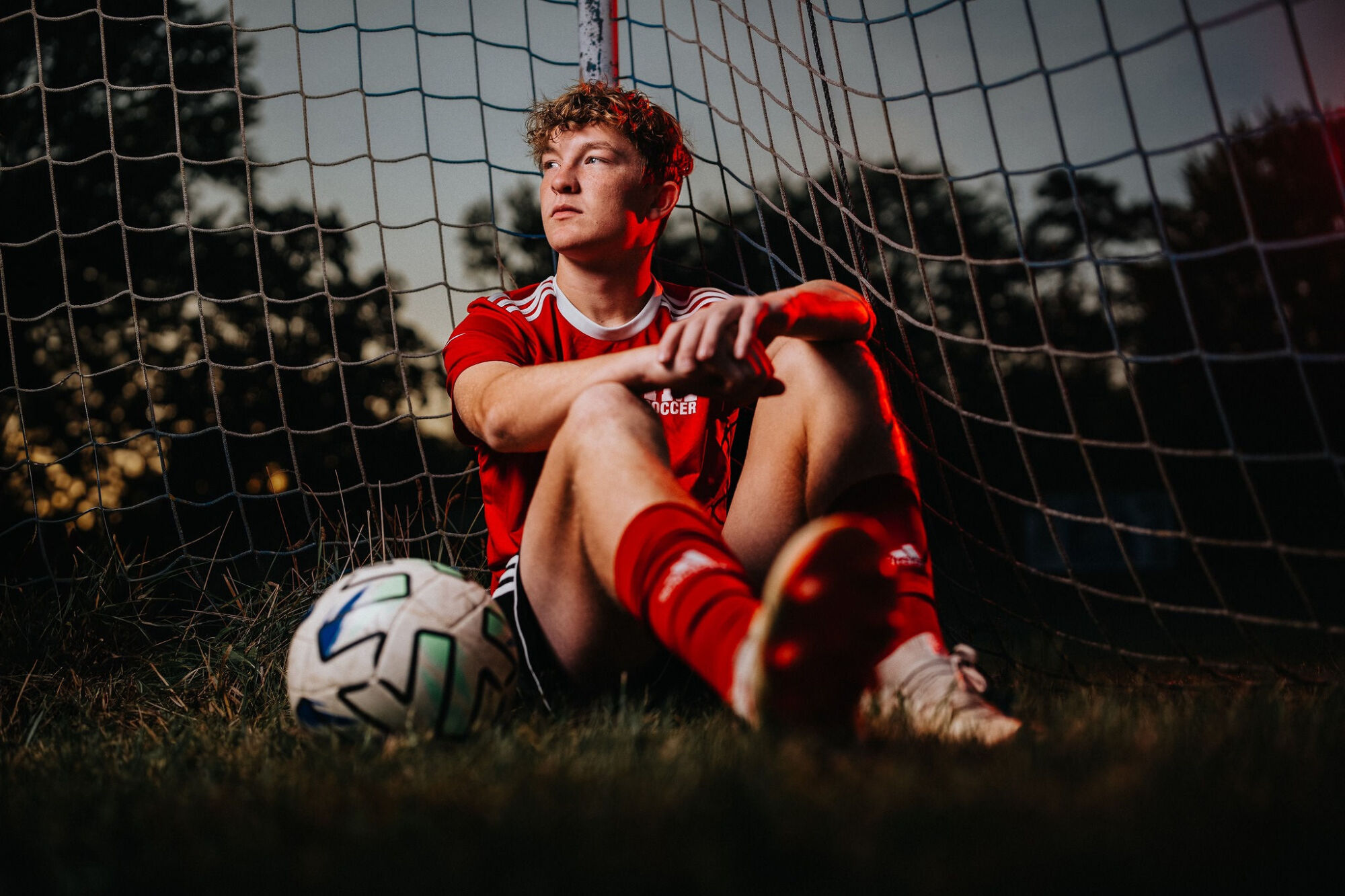 Soccer senior photo with ball on open field in team uniform