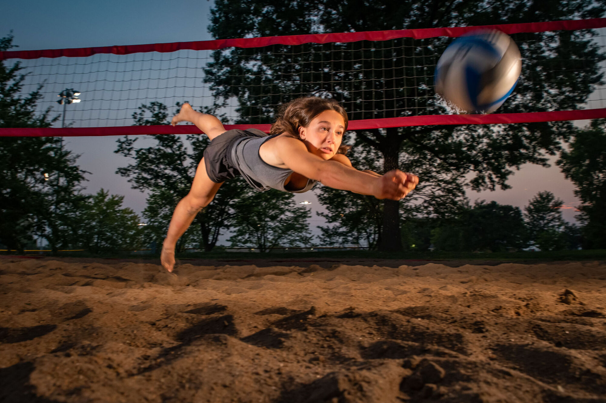 Beach volleyball senior portrait on sand court with ball