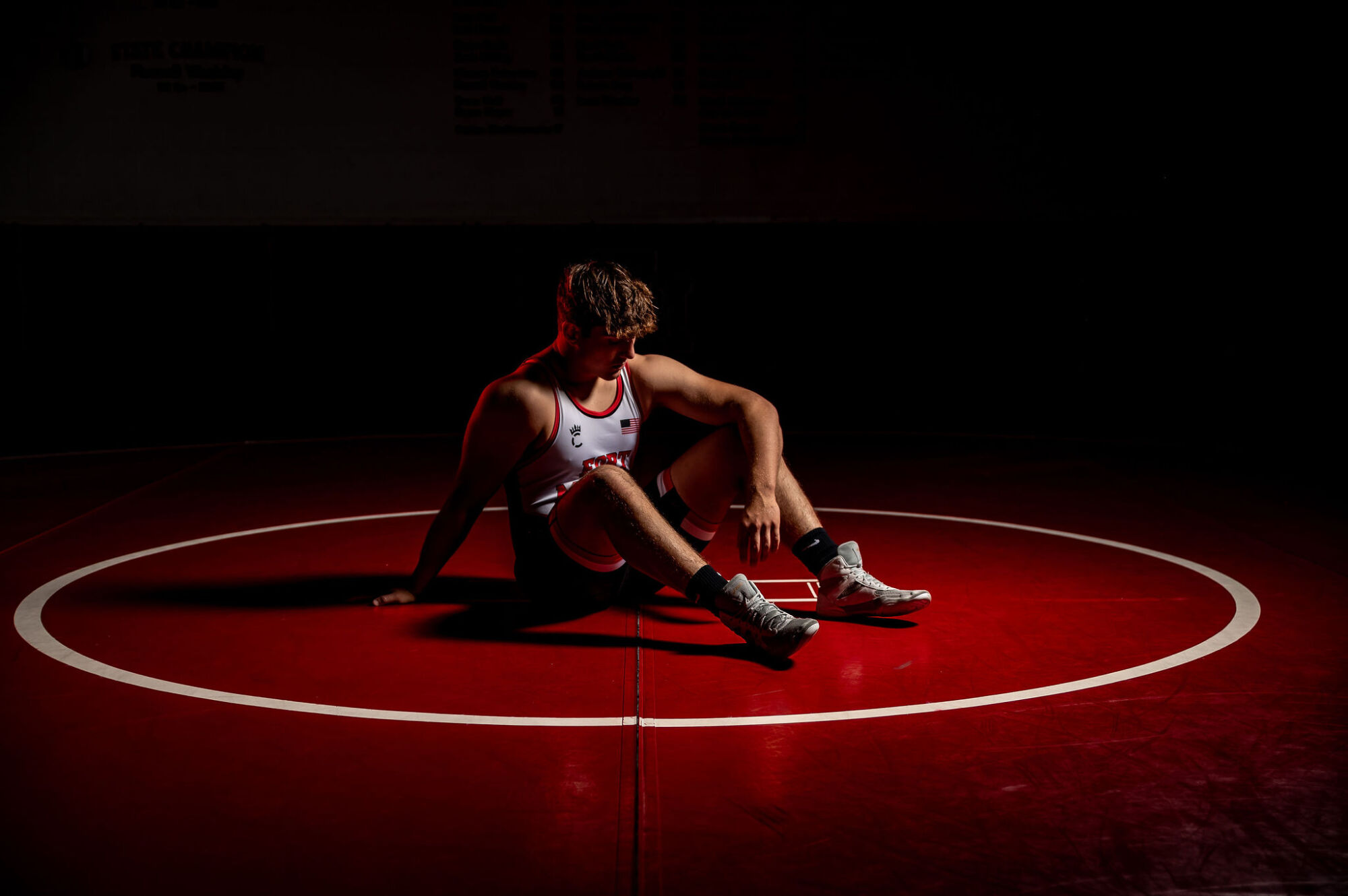 Wrestling senior portrait on mat in competition singlet with dramatic lighting