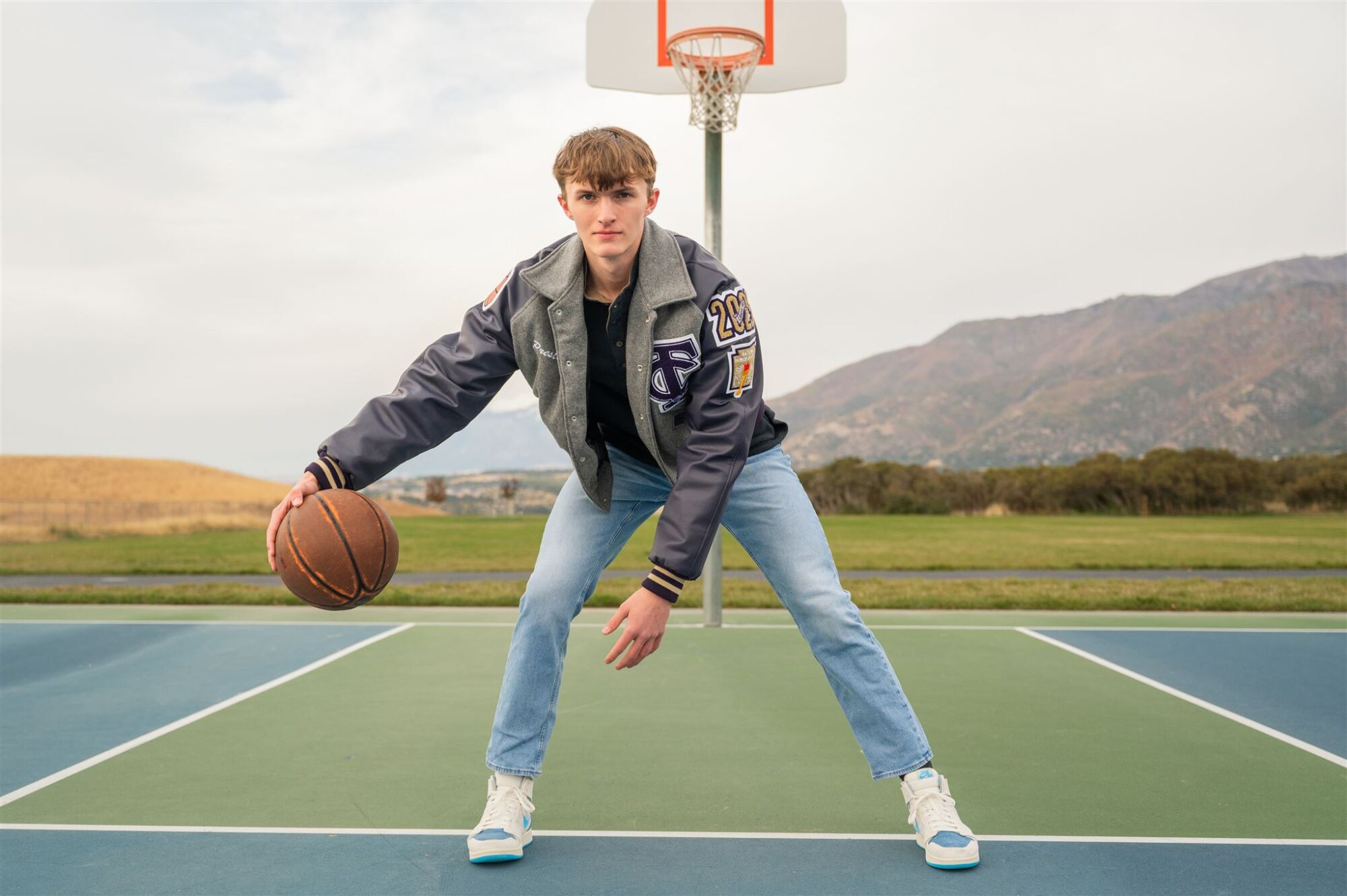 Basketball senior portrait with ball on gymnasium court under lights