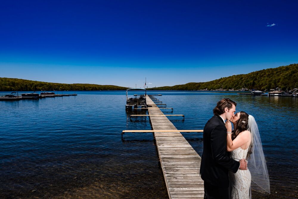 Couple kisses near dock for lake wedding photography