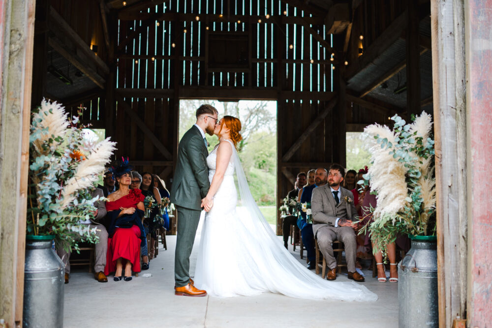 Newlyweds kiss in a barn during rustic boho weddings